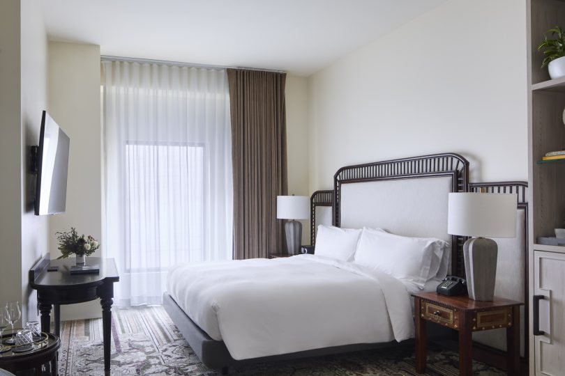 A hotel room with a large bed, two nightstands, a TV, and a window