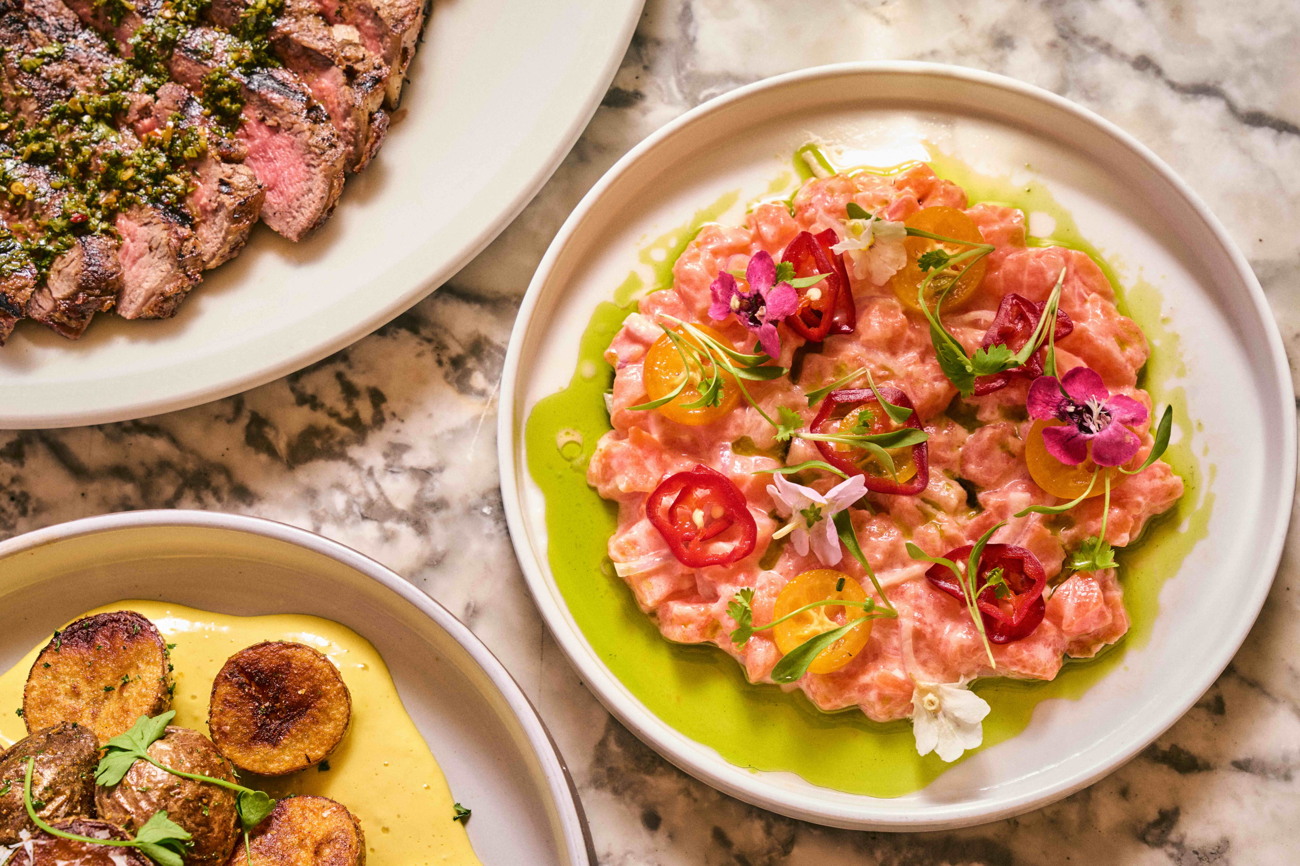 Three plates of food on a marble table